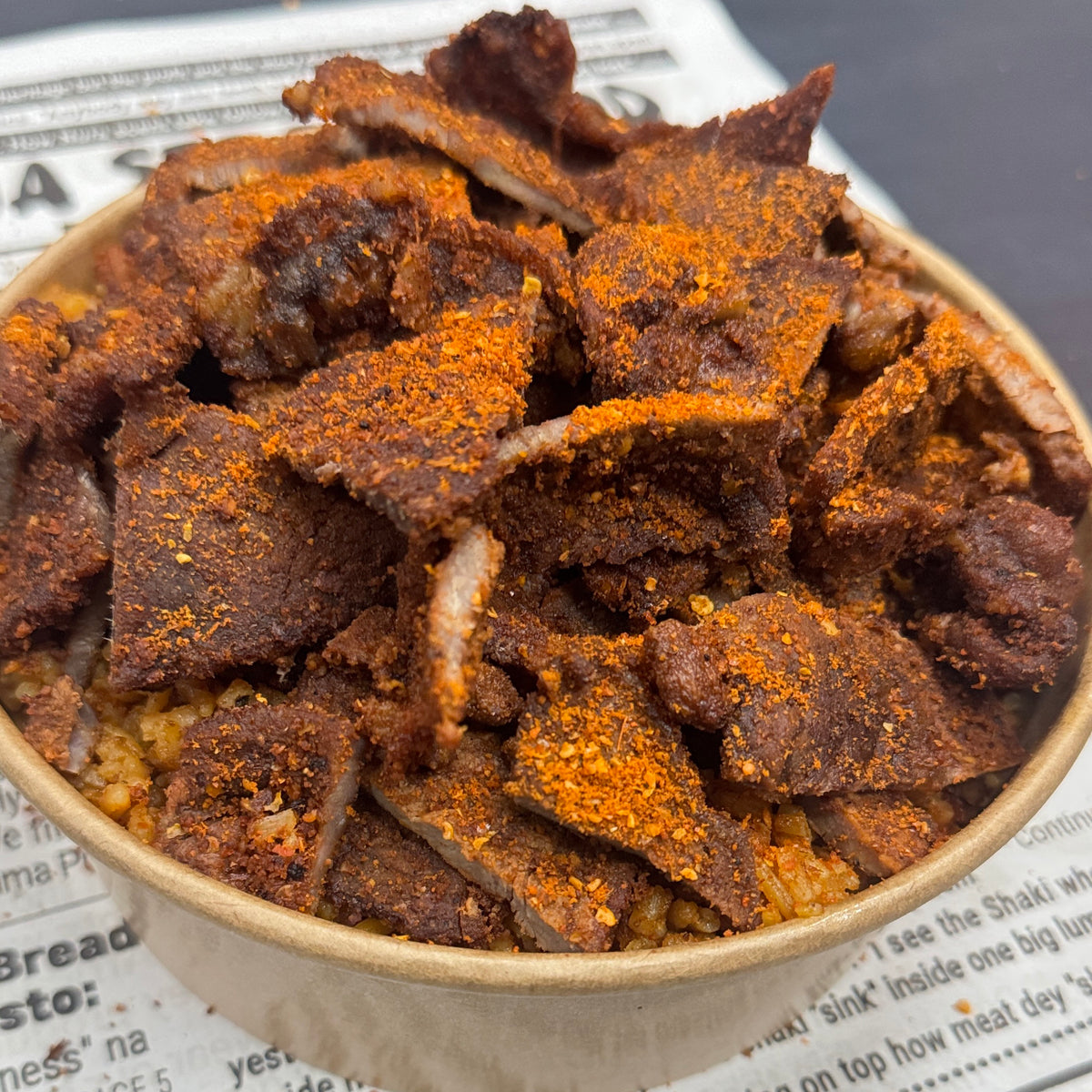 Large portion of home cooked Nigerian Jollof Rice topped with flame grilled Beef Suya.
